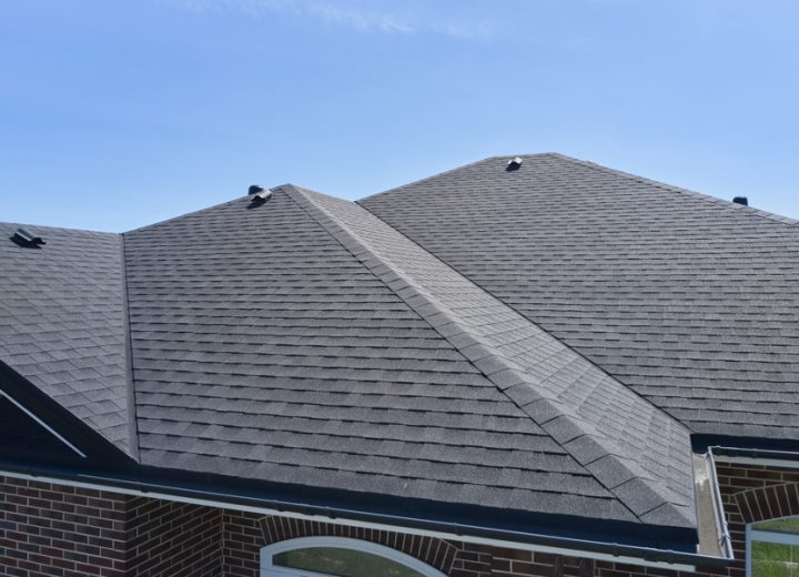 Close-up view of a residential roof with gray architectural asphalt shingles installed across multiple gables and ridges on a brick home — roofing coordinated by Legacy Ridge Exteriors.
